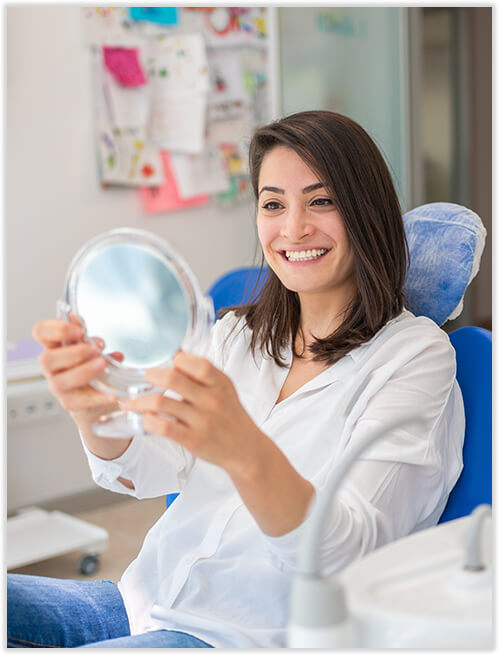woman looking at her smile in a mirror