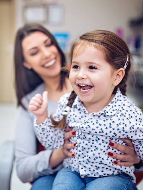 mother holding her daughter at her dental appointment